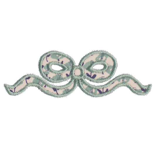 Close up of Deacon Lane's applique bow design in a Liberty of London like navy floral print.