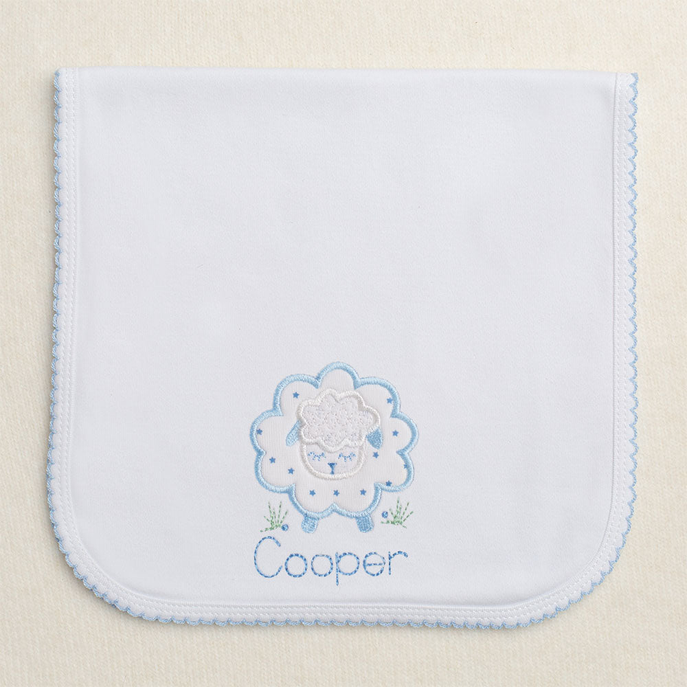 Blue trimmed picot burp pad with a fluffy blue applique sheep in a tiny blue star print with an embroidered name