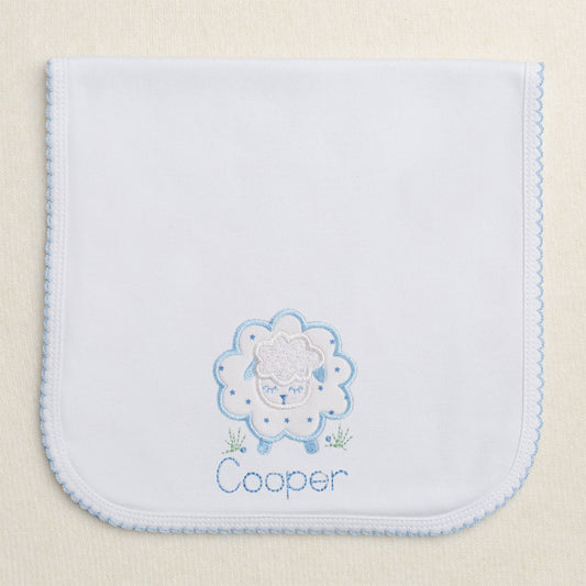 Blue trimmed picot burp pad with a fluffy blue applique sheep in a tiny blue star print with an embroidered name