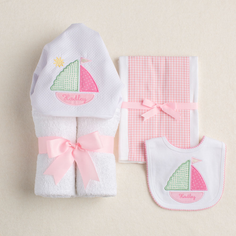 Charming 3 piece boutique baby gift set featuring Deacon Lane's exclusive pink sailboat applique.  The three pieces include a hooded towel, a fabric burp pad, and a bib.  The child's name is the ultimate in customization as it is tucked away in the bottom of the boat.