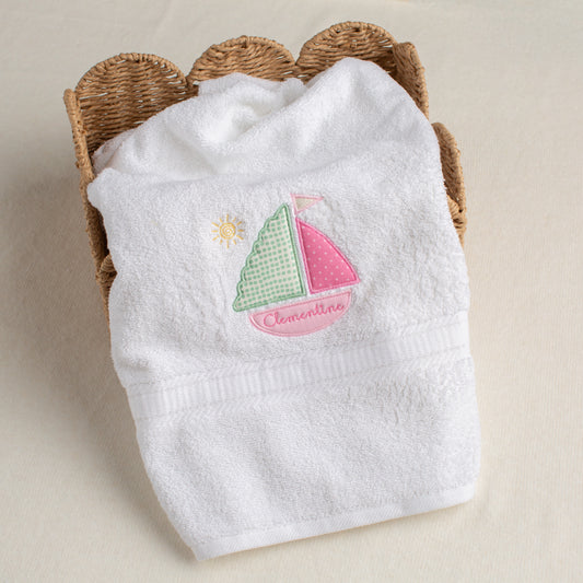 White cotton bath towel with pink appliqued sailboat with custom embroidery that personalizes the item for unique gift giving.