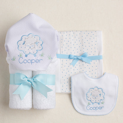 3 piece boutique baby set featuring Deacon Lane's Blue Fluffy Sheep collection with a hooded towel, fabric burp pad, and bib with picot trim.  2 of the items are personalized with a child's name embroider on the item.