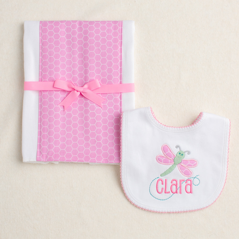 2 piece gift set with picot bib with a dragonfly applique and a custom embroidered name that is integrated into the design along with a fabric burp pad in a pink hex fabric.