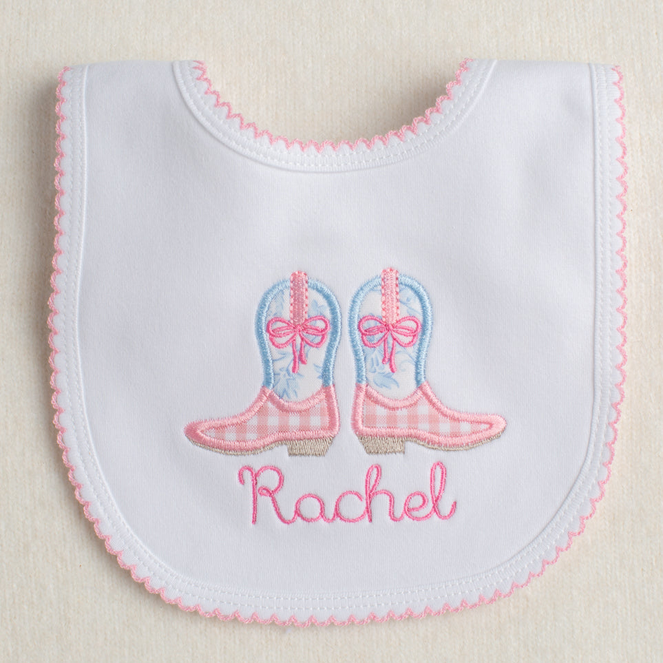 White bib with pink picot trim with appliqued pink and blue cowboy boots ready for easy gift giving
