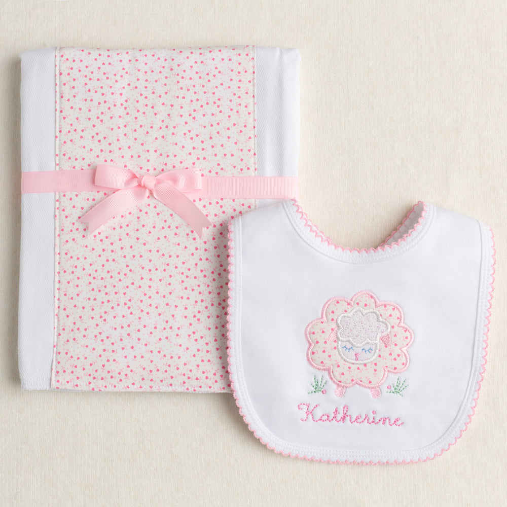 Exclusive Deacon Lane 2 piece gift set with appliqued bib and fabric burp pad with a pink floral sheep motif.