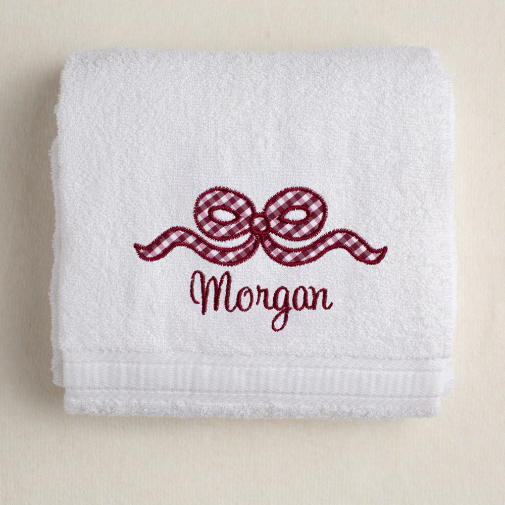 white bath towel with a maroon appliqued bow