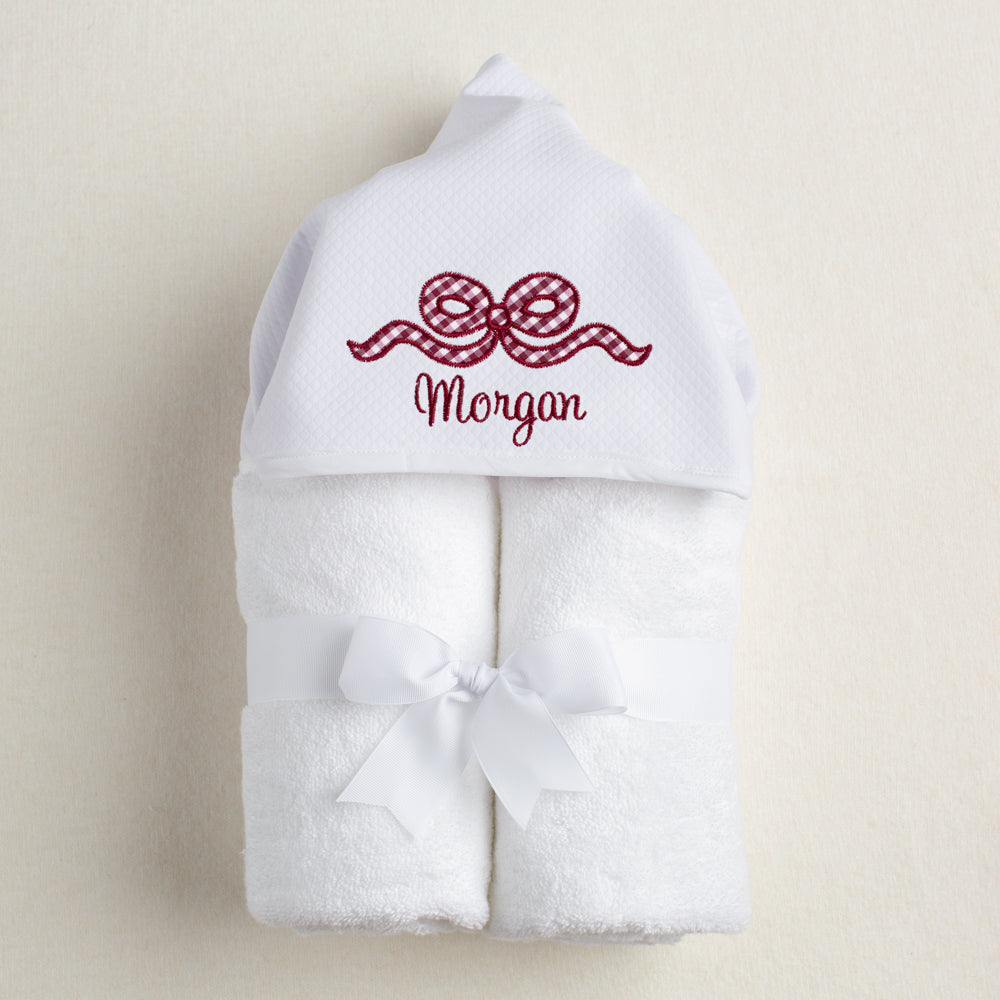white hooded towel for Aggie fans with a maroon appliqued bow and an embroidered, personalized name.