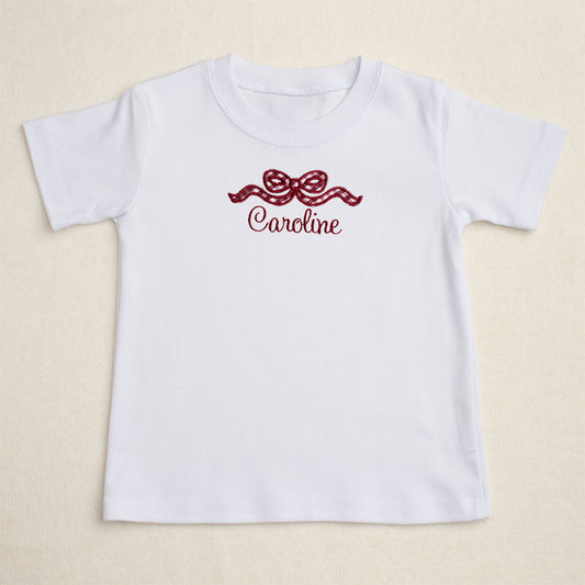 White t-shirt with a maroon check applique bow with a personalized name for Aggie fans.