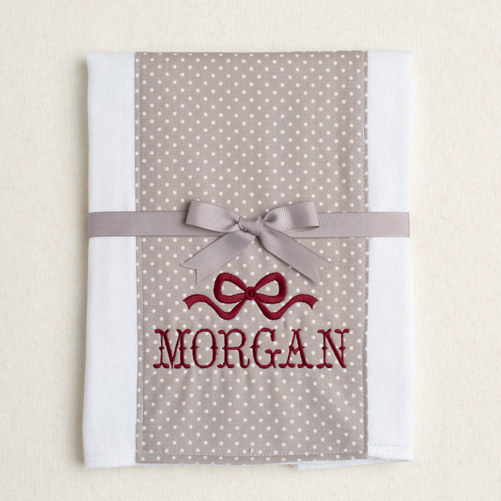Cotton burp cloth with grey polka dots and a maroon embroidered name and special bow for Texas A + M fans