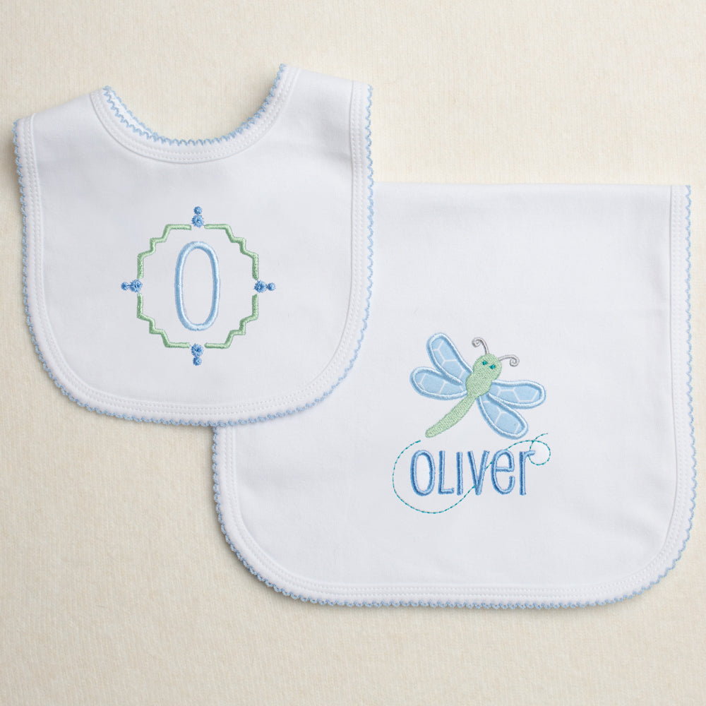 Baby gift set with a monogrammed picot trimmed white knit bib along with a picot trimmed burp pad with a dragonfly applique and a personalized name.