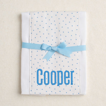 Boutique baby burp pad with blue star fabric panel sewn down the center.  Personalized with embroidery and packaged tied with a grosgrain bow.