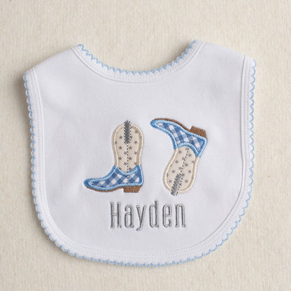 White boutique Western themed bib with applique cowboy boot and a personalized embroidered name.