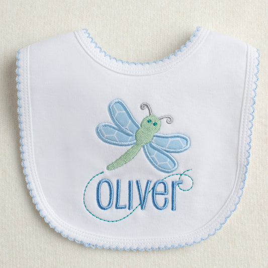 White knit bib with blue picot trim featuring an exclusive Deacon Lane applique design of a dragonfly.  Bib can be embroidered with the child's name for a one of a kind gift.
