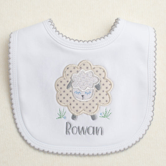 white cotton bib with grey picot trim with a grey star sheep applique and a personalized embroidered name