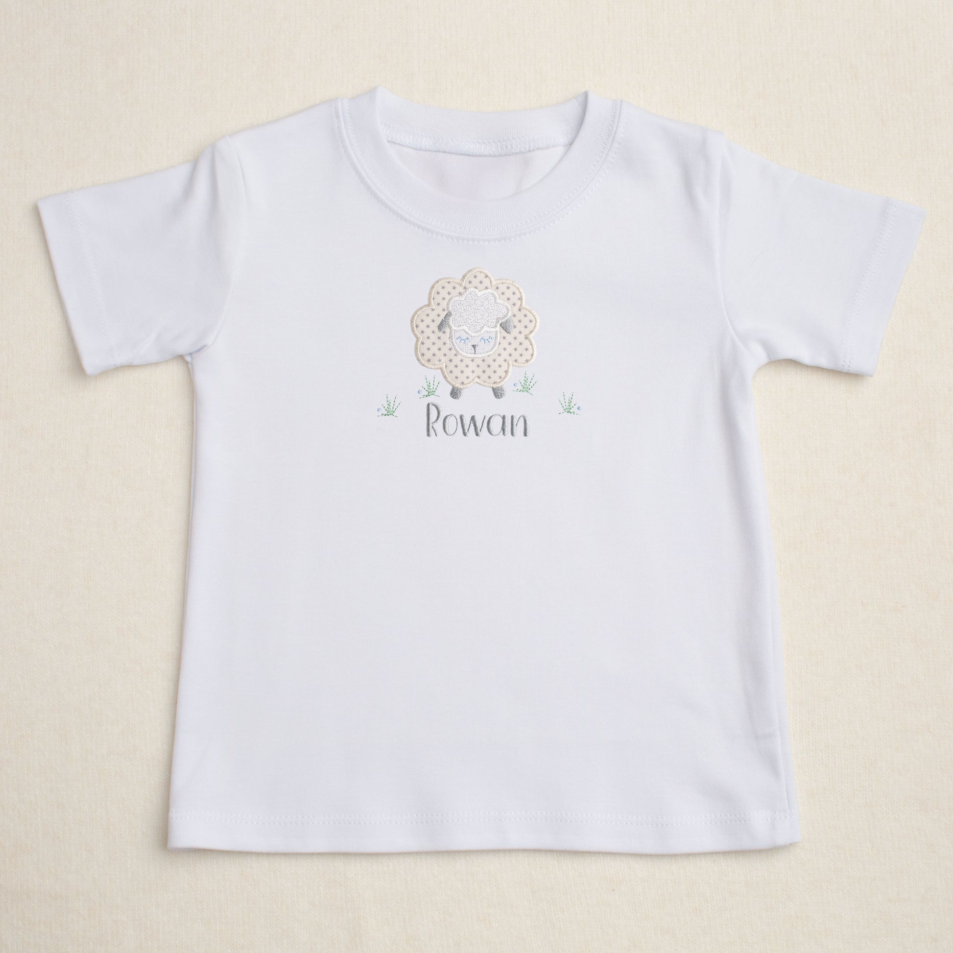 white t-shirt with Deacon Lane's Grey Fluffy Sheep applique in grey, cream, and white