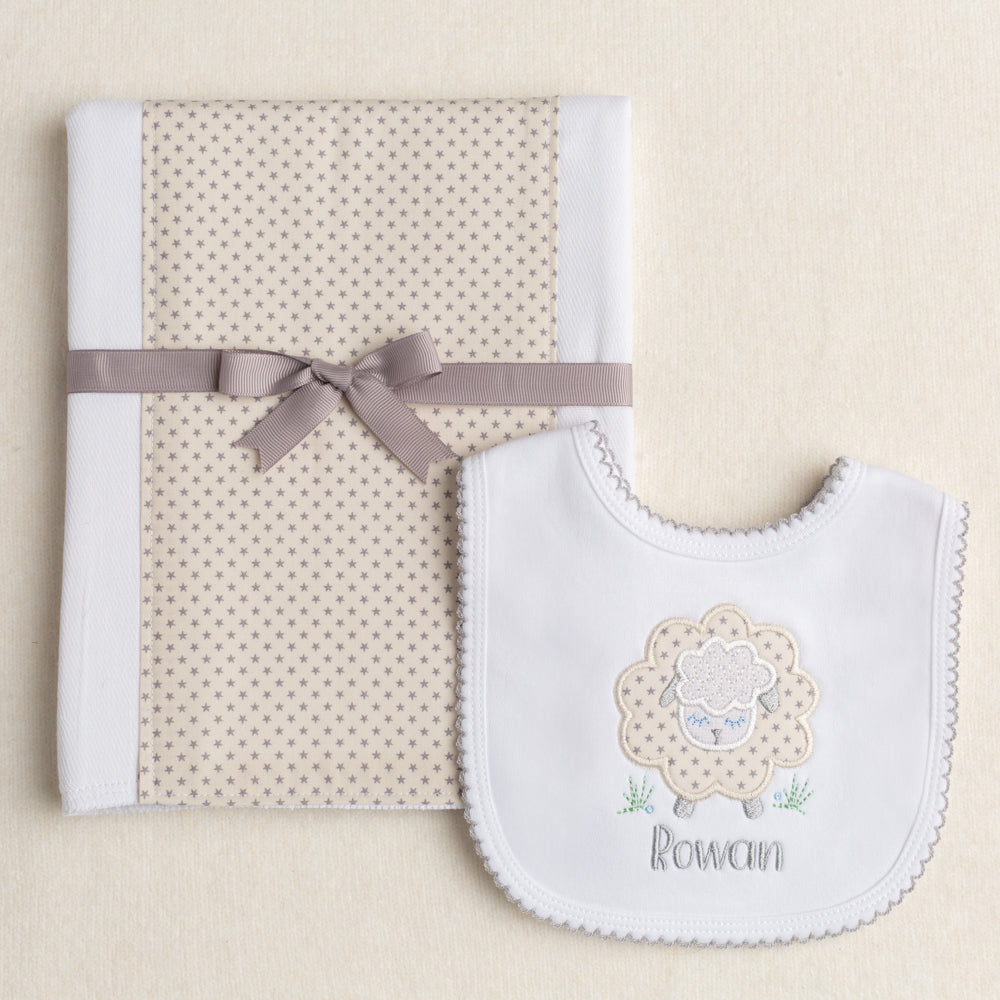 2 piece baby boutique gender neutral gift with a fabric burp pad and a white cotton knit bib in grey and cream tones featuring a sheep motif and a personalized name.
