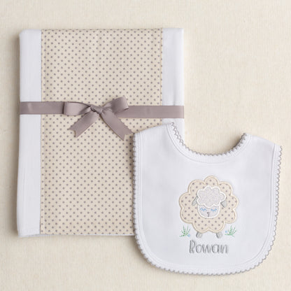 2 piece baby boutique gender neutral gift with a fabric burp pad and a white cotton knit bib in grey and cream tones featuring a sheep motif and a personalized name.