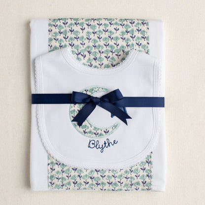 Boutique baby gift set of a burp pad with a fabric panel down the center and a bib appliqued with a moon and star motif made of fabric reminiscent of a Liberty print