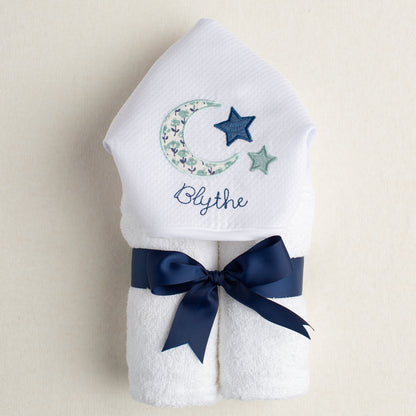 Personalized boutique baby gift - White hooded towel with embroidered moon, star, and name 'Blythe' on a beige background