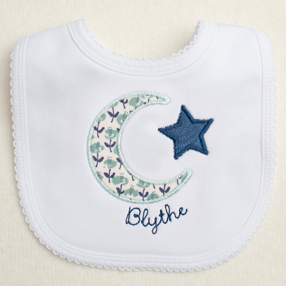 white cotton bib with picot edge with moon and star applique in navy and seafoam fabrics personalized with an embroidered name