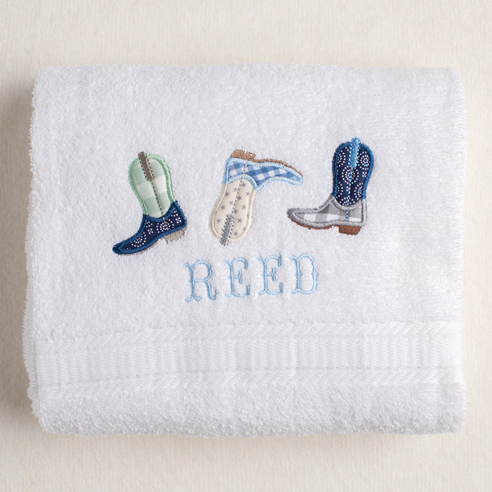 white bath towel with a western or cowboy theme featuring Deacon Lane's exclusive appliqued cowboy boots.  Personalization is in a western cowboy fishtail font.