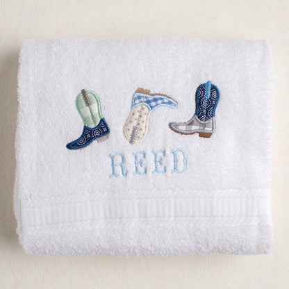 white bath towel with a western or cowboy theme featuring Deacon Lane's exclusive appliqued cowboy boots.  Personalization is in a western cowboy fishtail font.