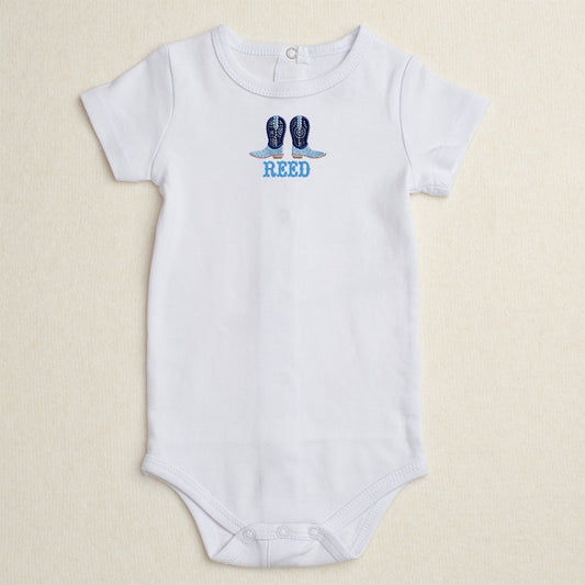 White baby onesie with custom blue cowboy boot design and personalized name embroidered on bodysuit