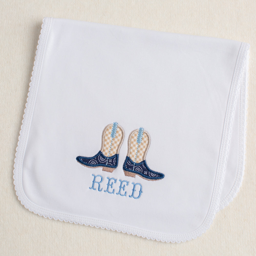 Picot trimmed burp pad with a western theme cowboy boot applique with a name embroidered beneath the boots.
