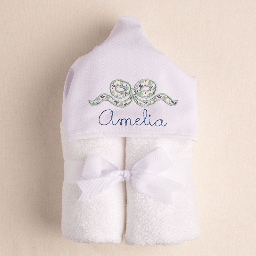White hooded towel with a navel floral bow applique in a Liberty-like print with a personalized name.