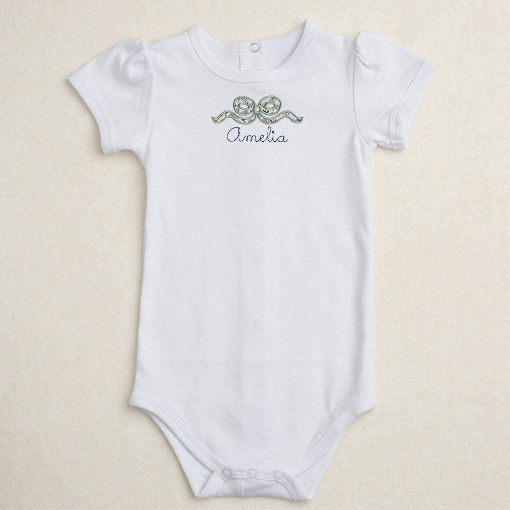 white onesie with applique bow in navy floral print