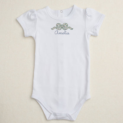 white onesie with applique bow in navy floral print