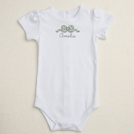 white onesie with applique bow in navy floral print