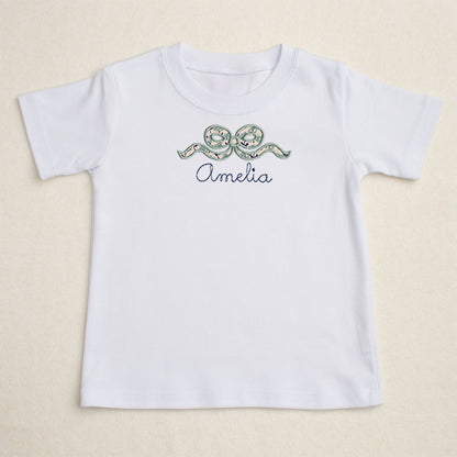 Girls white t-shirt with Deacon Lane's applique bow design in a navy and seafoam/sage floral.