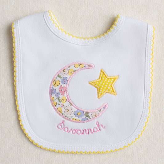 Personalized Baby bib with appliqued floral moon and star design on a beige background