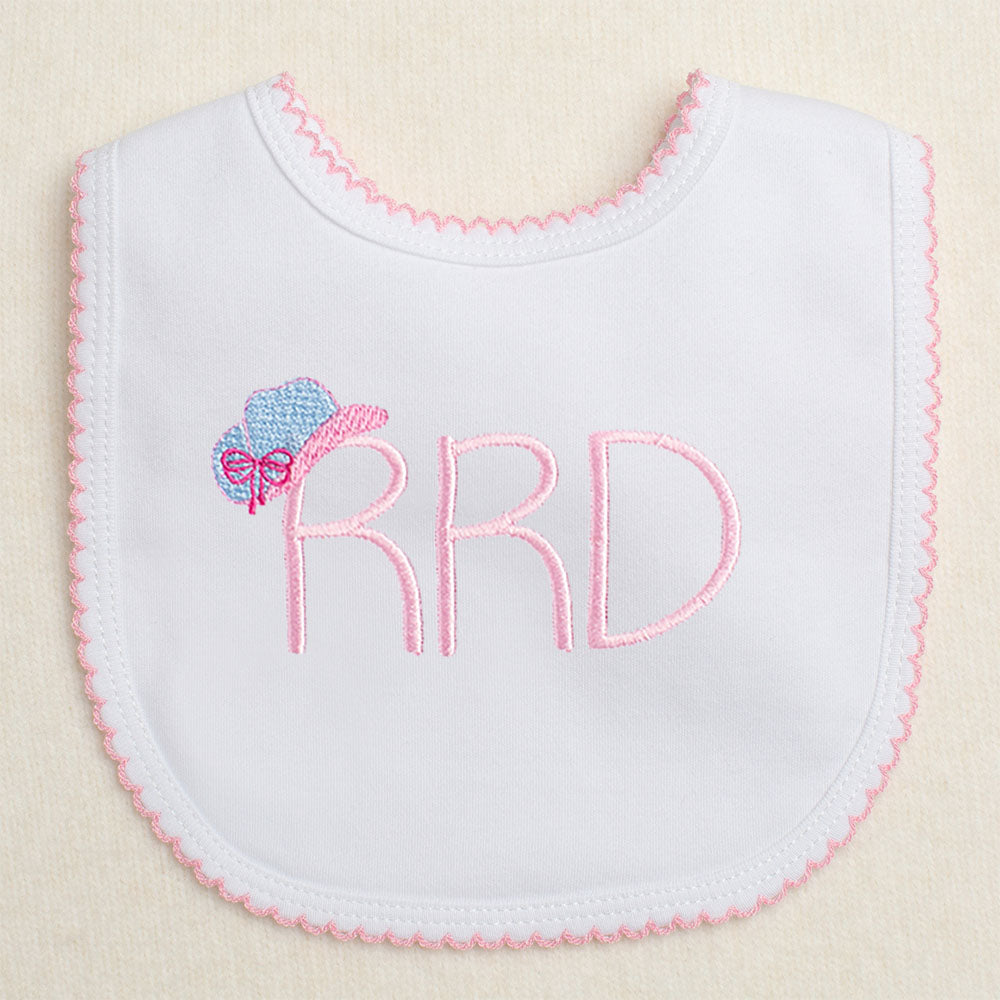 white bib with monogram and an embroidered cowgirl hat