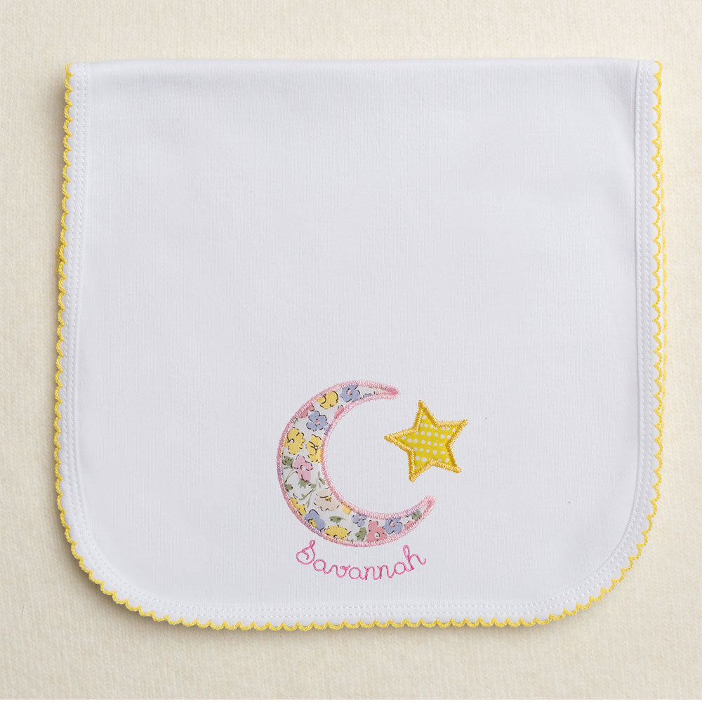 Yellow picot trimmed burp pad with pink floral moon and star applique with embroidered name circling the moon.