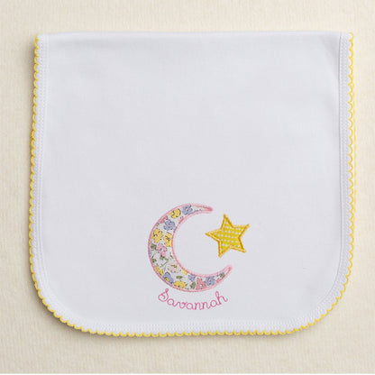 Yellow picot trimmed burp pad with pink floral moon and star applique with embroidered name circling the moon.