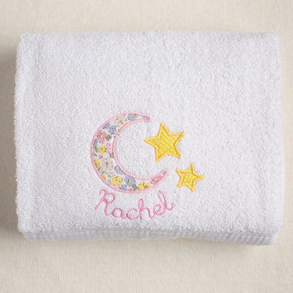 White towel with floral moon and stars design and embroidered name 'Rachel' on a beige background