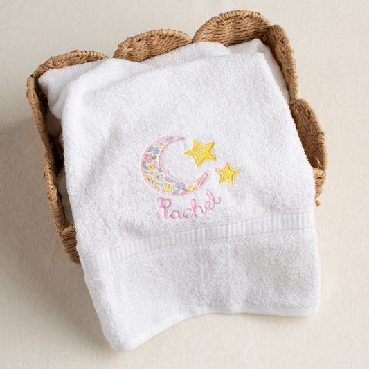 Beautiful white bath towel with a personalized embroidered name under a hand-done pink floral applique of a moon and stars pattern that is reminiscent of Liberty of London.