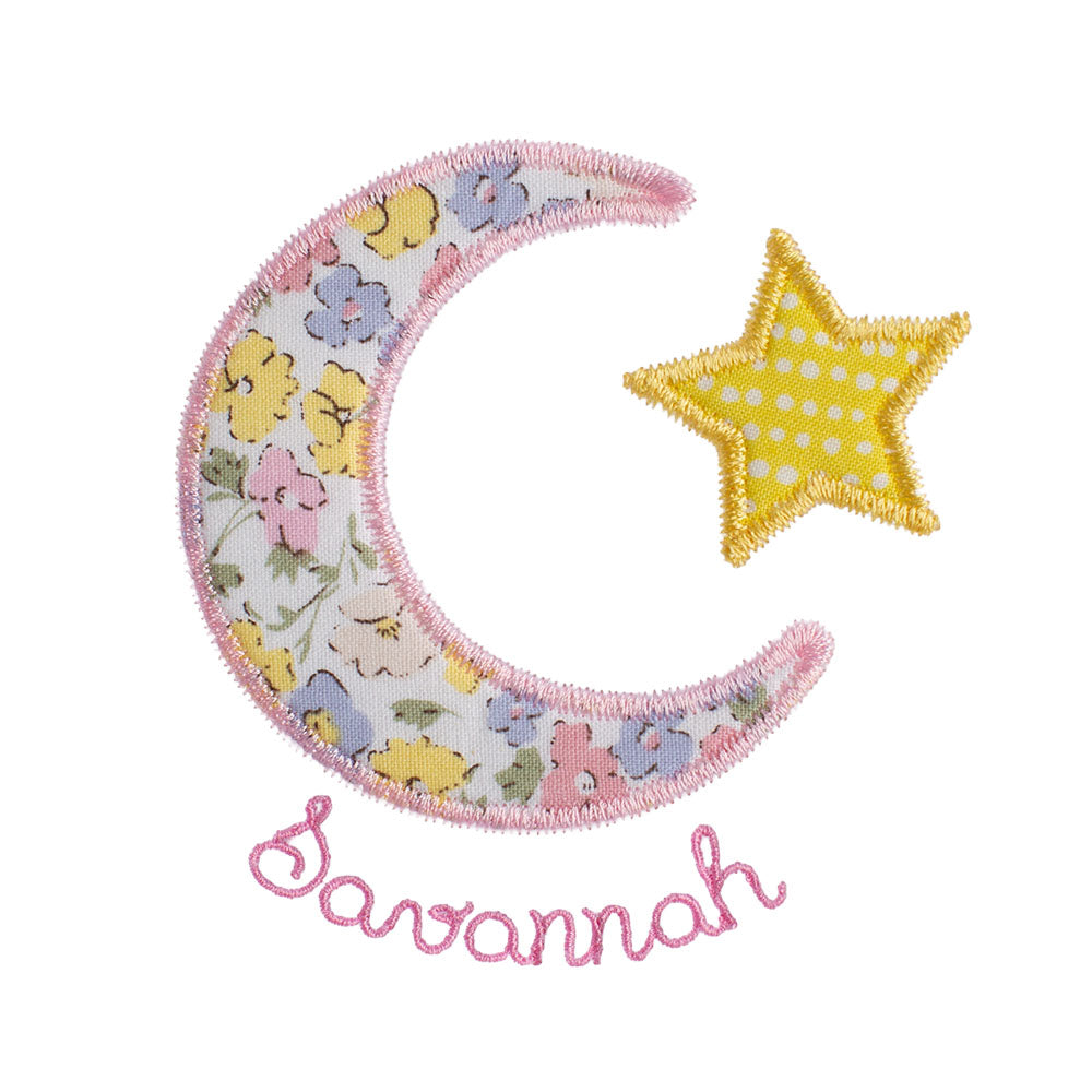 Close up of a moon and star applique featuring a pink floral fabric that is similar in look to a Liberty of London print.

