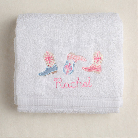 Folded towel with embroidered boot designs and the name 'Rachel'.