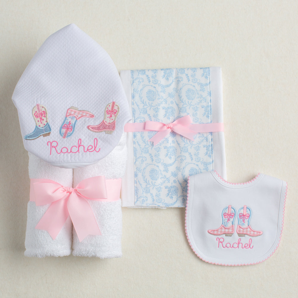 Personalized baby gift set with a Shabby Chic Cowgirl motif featuring appliqued cowboy boots in pink check and blue toile.  Includes a hooded towel, a fabric burp pad, and a personalized bib.
