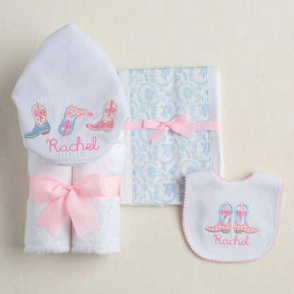 Personalized baby gift set with a Shabby Chic Cowgirl motif featuring appliqued cowboy boots in pink check and blue toile.  Includes a hooded towel, a fabric burp pad, and a personalized bib.