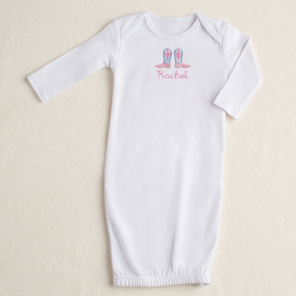 White baby gown with appliqued Shabby Chic Cowgirl boots featuring a blue floral toile fabric and personalized with a name on a beige background