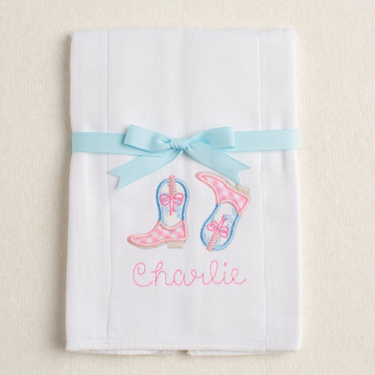Personalized burp pad with appliqued cowboy/cowgirl boots in a pink check and and blue floral toile.  Packaged folded and tied with a grosgrain ribbon
