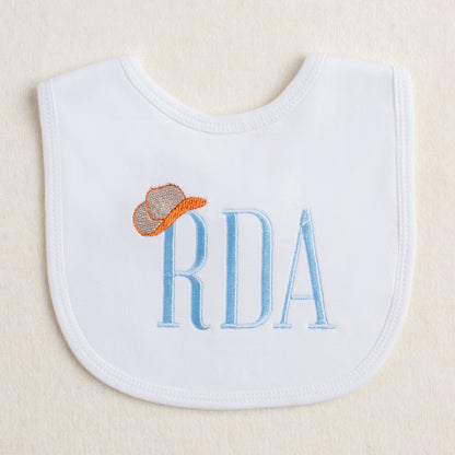 White bib with Deacon Lane's Tip Your Hat Monogram design in burnt orange and other colors.