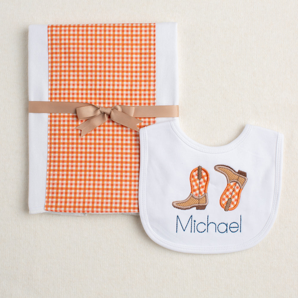 Close up of Deacon Lane's 2 piece Kickin' Boots burp pad and bib set in burnt orange.