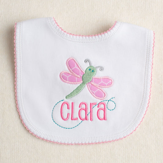 cotton bib with pink picot edging with a custom applique of a pink and green dragonfly and an embroidered, personalized name