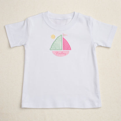 White t-shirt with applique personalized sailboat design on a beige background