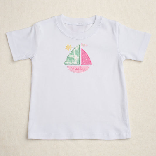 White t-shirt with applique personalized sailboat design on a beige background